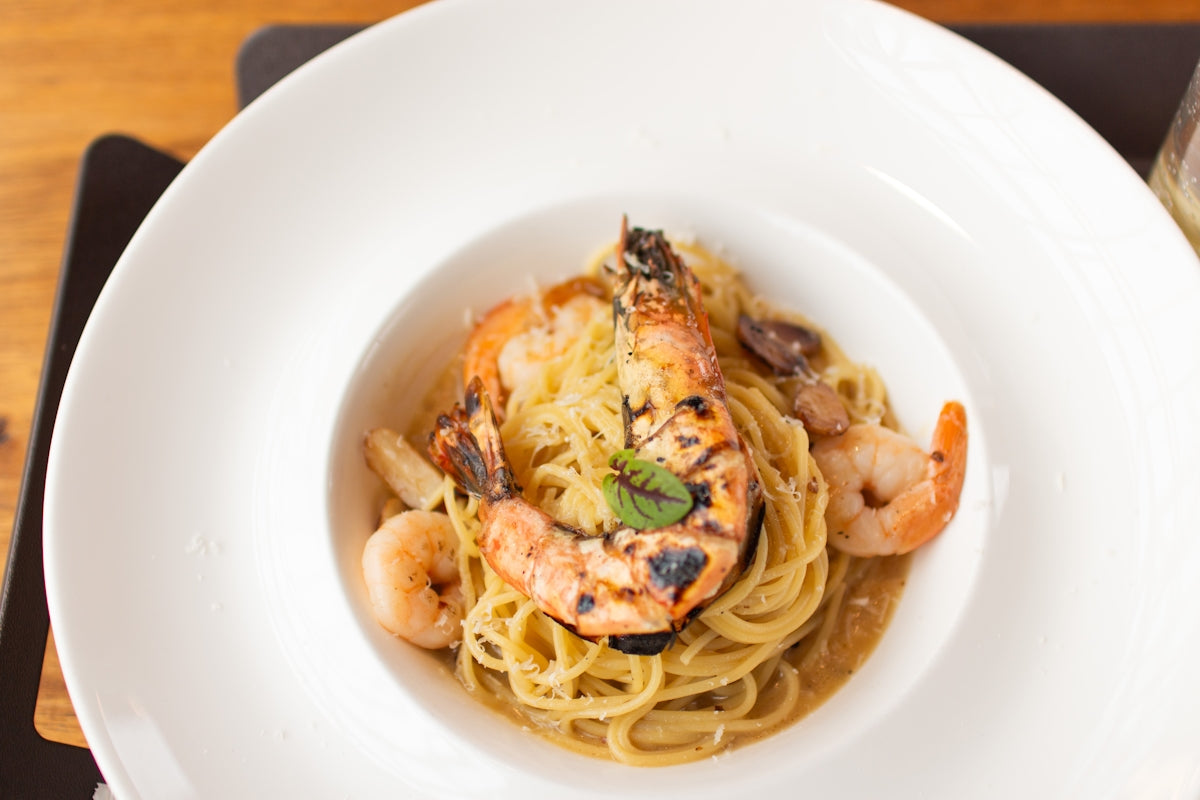 A white plate topped with pasta and shrimp