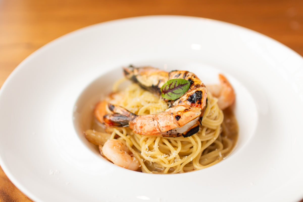 A white plate topped with pasta and shrimp