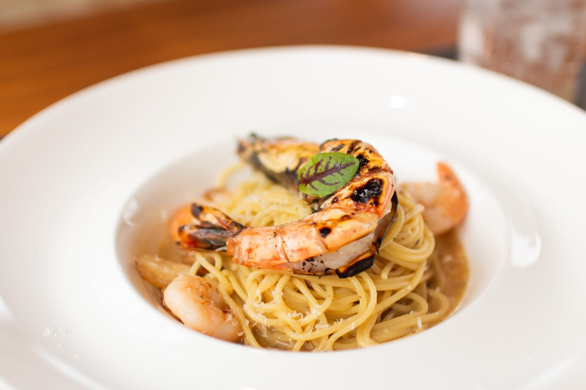 A white plate topped with pasta and shrimp
